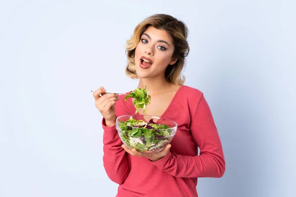 Teenager woman with salad isolated on blue background