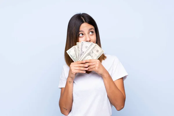 Joven Mujer Sobre Aislado Azul Fondo Tomando Montón Dinero — Foto de Stock