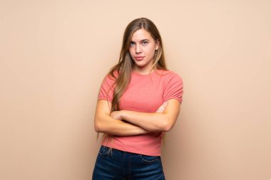 Genç sarışın kız izole bir hayat sürüyor. Kollarını kavuşturuyor.