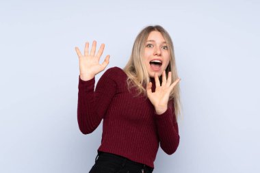 Soyutlanmış mavi arka planda genç sarışın kadın gergin ve korkmuş.