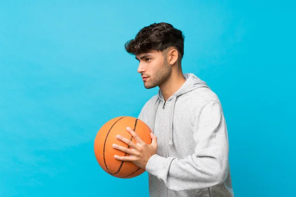 Joven Hombre Guapo Sobre Fondo Azul Aislado Con Pelota Baloncesto —  Fotos de Stock