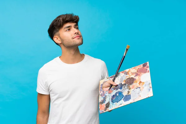 Jovem Bonito Homem Sobre Isolado Fundo Azul Segurando Uma Paleta — Fotografia de Stock