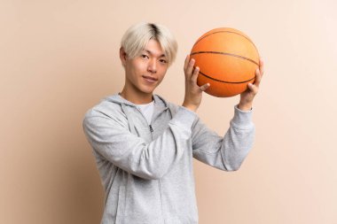 Basketbol topuyla izole edilmiş Asyalı genç adam.