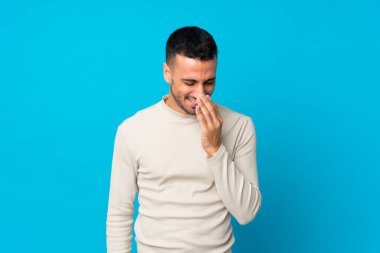 Soyutlanmış mavi arka planı olan genç adam çok gülümsüyor.