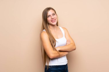 Sarışın genç bir kız kollarını kavuşturup ileriye bakıyor.