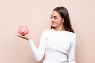 Tecrit edilmiş genç bir kadın elinde büyük bir kumbara tutuyor.