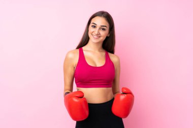 İzole edilmiş pembe arka planda boks eldivenli genç bir kız.