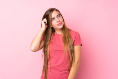 Genç sarışın kız pembe arka planda kuşkuları ve kafa karıştırıcı bir yüz ifadesi var.