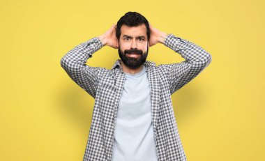 Handsome man with beard frustrated and takes hands on head