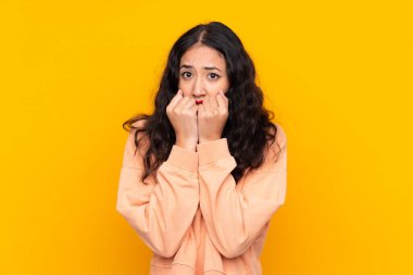 İspanyol Çinli kadın, izole edilmiş sarı arka planda gergin ve korkmuş bir şekilde elleriyle suni teneffüs yapıyor.