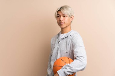 Basketbol topuyla izole edilmiş Asyalı genç adam.