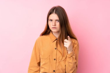 İzole edilmiş pembe arka planı olan Ukraynalı genç kız hayal kırıklığına uğramış ve ön tarafı işaret ediyor.