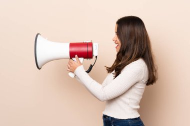 Tecrit edilmiş arka planda genç Kolombiyalı bir kız megafondan bağırıyor.