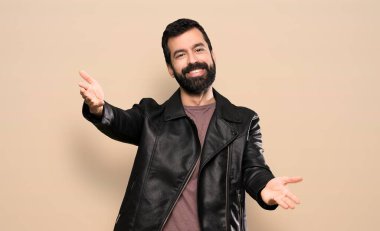 Sakallı yakışıklı adam sunuyor ve davet ediyor.