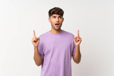 Genç yakışıklı, soyutlanmış beyaz arka plan şaşırmış ve yukarı bakıyor.