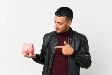 Soyutlanmış beyaz arka planı olan genç bir adam büyük bir kumbara tutuyor.