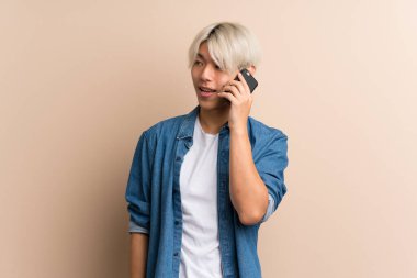 Asyalı genç bir adam izole edilmiş arka planda cep telefonuyla sohbet ediyor.