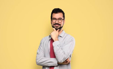 Gözlüklü, sakallı yakışıklı ve izole edilmiş sarı arka planda mutlu bir adam.