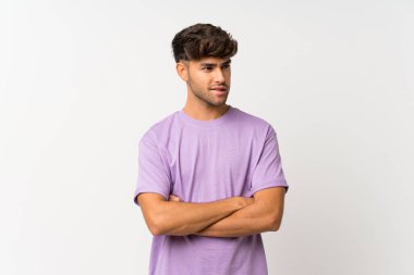 Soyutlanmış beyaz arka planda, kafası karışmış genç yakışıklı bir adam.