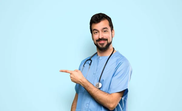 Cirurgião Médico Homem Apontando Dedo Para Lado Sobre Fundo Azul — Fotografia de Stock