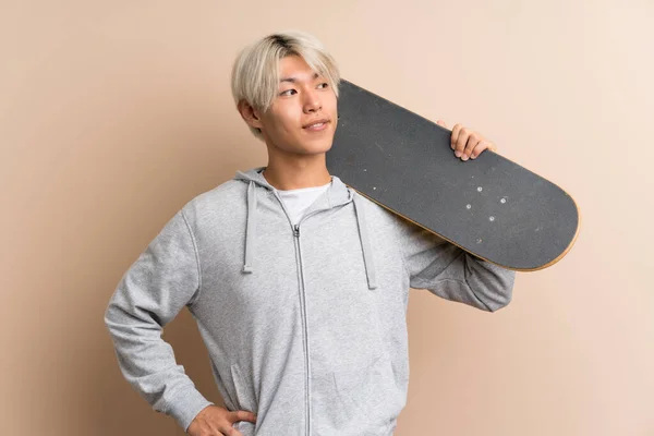 Joven Asiático Hombre Sobre Aislado Fondo Con Skate Buscando Lado — Foto de Stock
