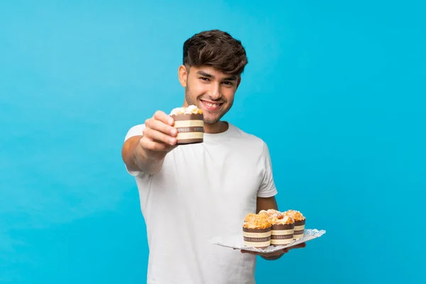 Junger Gutaussehender Mann Auf Isoliertem Blauem Hintergrund Hält Mini Kuchen — Stockfoto