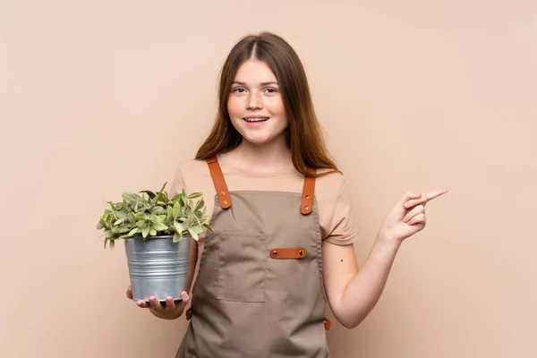 Adolescente Ucraniana Jardinero Chica Sosteniendo Una Planta Señalando Dedo Lado — Foto de Stock