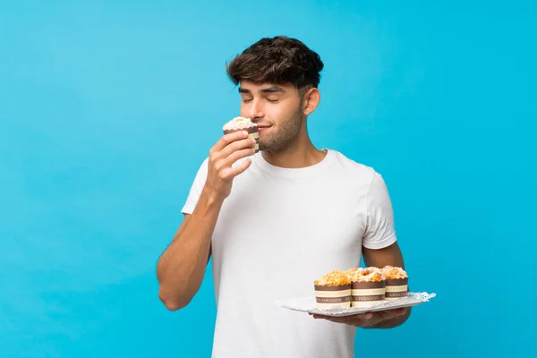 Jonge Knappe Man Geïsoleerde Blauwe Achtergrond Met Mini Cakes — Stockfoto
