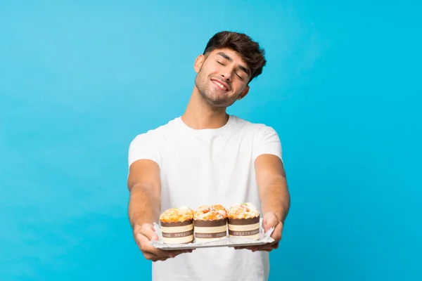 Ung Stilig Man Över Isolerad Blå Bakgrund Håller Mini Kakor — Stockfoto