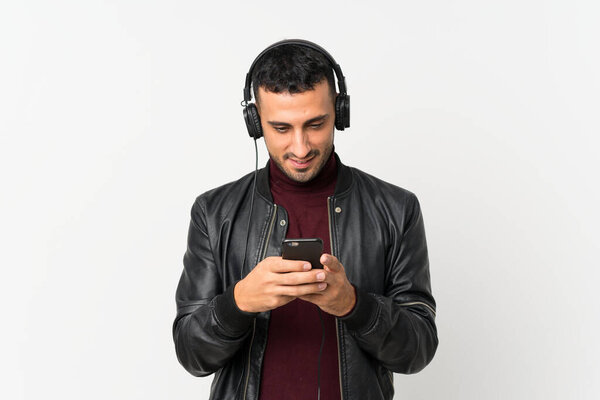 Young man over isolated white background using the mobile with headphones