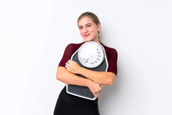 Teenager girl with weighing machine over isolated white background with weighing machine