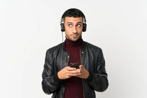 Молодий Чоловік Над Ізольованим Білим Тлом Допомогою Мобільного Телефону Навушниками — стокове фото