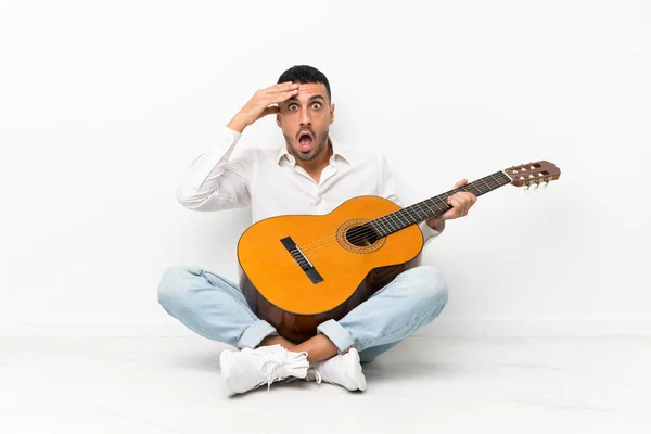 Jongeman Zittend Vloer Met Gitaar Met Verrassing Geschokte Gezichtsuitdrukking — Stockfoto