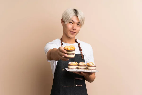 Jonge Aziatische Man Geïsoleerde Achtergrond Holding Mini Cakes Het Aanbieden — Stockfoto