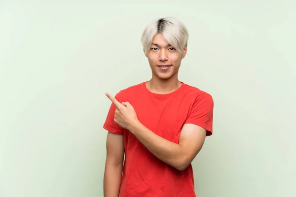Mladý Asijský Muž Přes Izolované Zelené Pozadí Ukazuje Stranu Prezentovat — Stock fotografie
