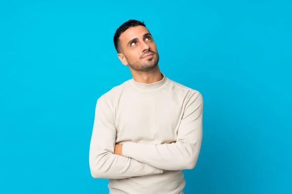 Joven Sobre Fondo Azul Aislado Mirando Hacia Arriba Mientras Sonríe — Foto de Stock