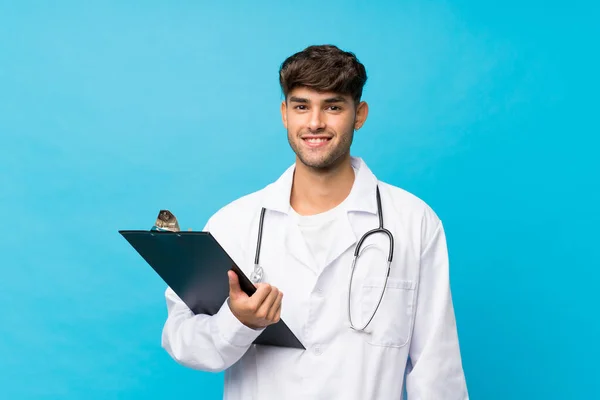 Jovem Homem Bonito Sobre Fundo Azul Isolado Com Vestido Médico — Fotografia de Stock