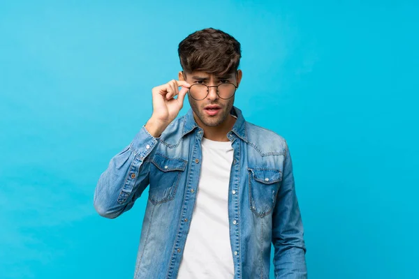Joven Hombre Guapo Sobre Fondo Azul Aislado Con Gafas — Foto de Stock