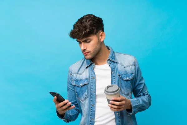 Soyutlanmış Mavi Arka Planda Genç Yakışıklı Bir Adam Elinde Kahve — Stok fotoğraf
