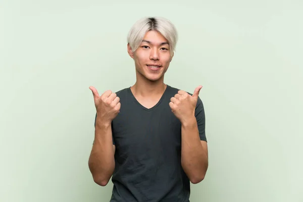 Joven Asiático Hombre Sobre Aislado Verde Fondo Con Pulgares Arriba — Foto de Stock