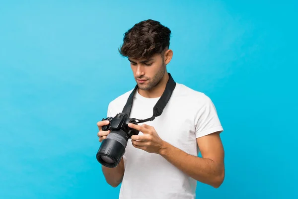 Giovane Bell Uomo Sfondo Blu Isolato Con Una Fotocamera Professionale — Foto Stock