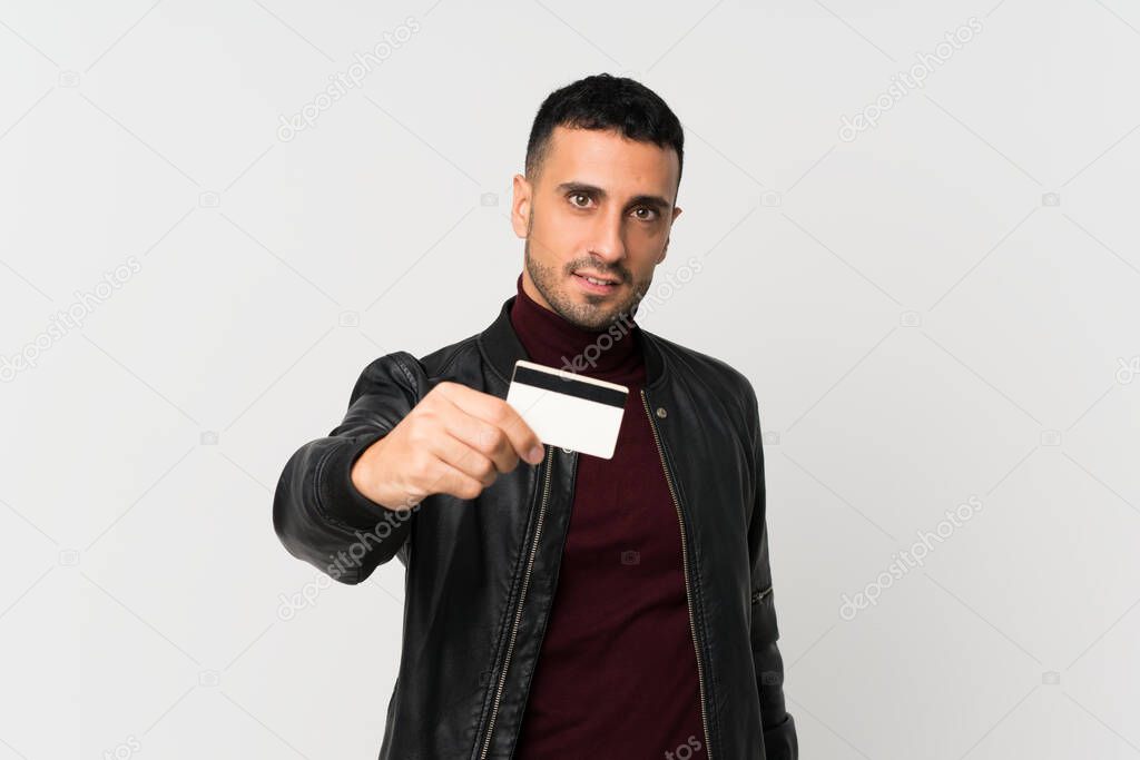 Young man over isolated white background holding a credit card