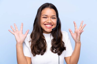 Genç tele pazarlamacı Kolombiyalı kadın mavi arka planda gülüyor.