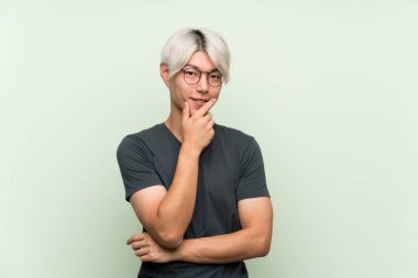 Gözlüklü ve gülümseyen yeşil bir geçmişi olan Asyalı genç bir adam.