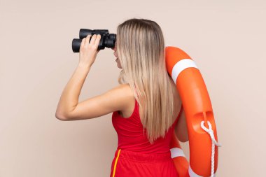 Tecrit edilmiş arka planda dürbünü olan cankurtaran kadın.