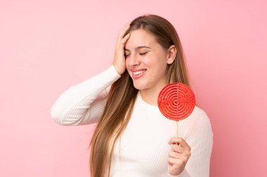 Soyutlanmış pembe arka planda lolipop tutan genç sarışın kız bir şey fark etti ve çözüme niyetlendi.