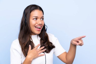Genç tele pazarlamacı Kolombiyalı kadın, izole edilmiş mavi arka planda.