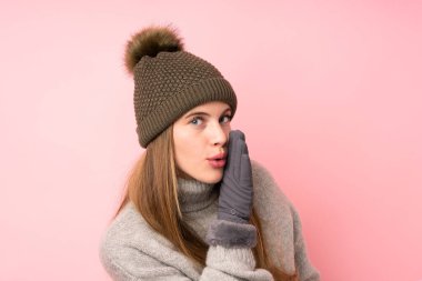 Kışlık şapkalı, pembe arka planda genç kız bir şeyler fısıldıyor.