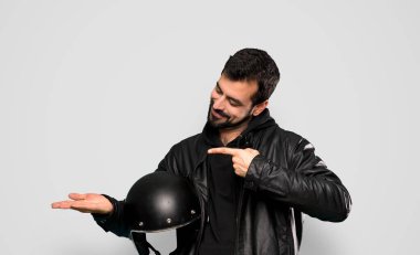 Biker man holding copyspace imaginary on the palm to insert an ad over isolated grey background