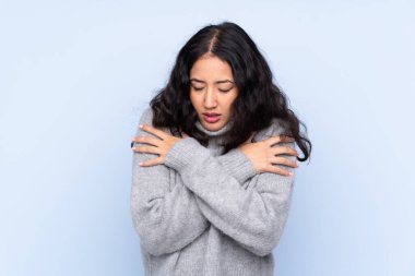 İspanyol Çinli kadın izole edilmiş mavi arka planda donuyor